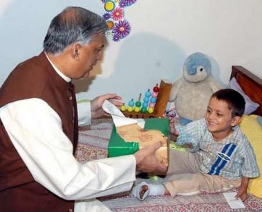 Pakistan's Prime Minister Shaukat Aziz (L) gives a gift to an injured child during his visit to a hospital in Islamabad October 16, 2005.