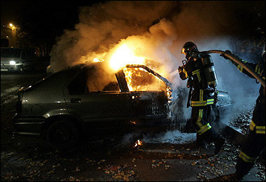 Firemen work on a burned car in the suburbs of Strasbourg, eastern France, 12 November 2005.