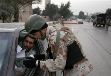 A soldier checks the identification card of an Iraqi driver at a checkpoint in Baghdad, Iraq, Tuesday Dec. 13, 2005.