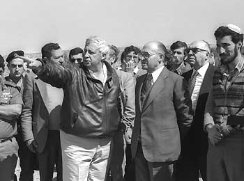 Israeli Prime Minister Menahem Begin (3rd R) listens to Israeli Agriculture Minister Ariel Sharon (C) during a visit to the West Bank settlement of Alon Moreh February 27, 1981 in this handout photo released by the Government Press Office.