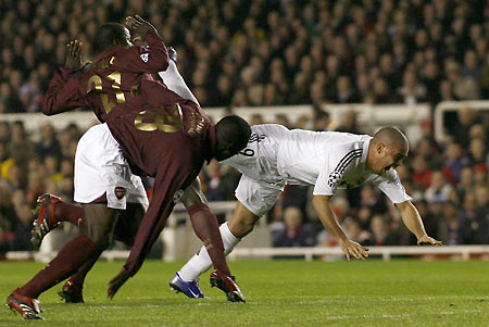 Real Madrid's Ronaldo (R) falls as he tries to evade the tackle of Arsenal's Emmanuel Eboue (L) and Kolo Toure (C) during their Champions League first knockout round second leg soccer match at Highbury, London March 8, 2006.