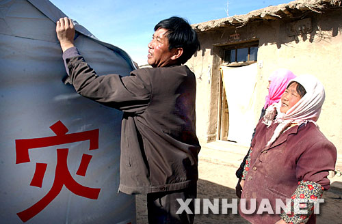 2003年11月12日，甘肅山丹縣李橋鄉(xiāng)劉莊村黨支部書記王升（左）在該村七社村民王金秀（右）家檢查抗震救災(zāi)帳篷密封情況。2003年10月25日，甘肅山丹縣發(fā)生6.1級地震后，該縣廣大黨員干部一直奮戰(zhàn)在抗震救災(zāi)第一線。 新華社發(fā) 